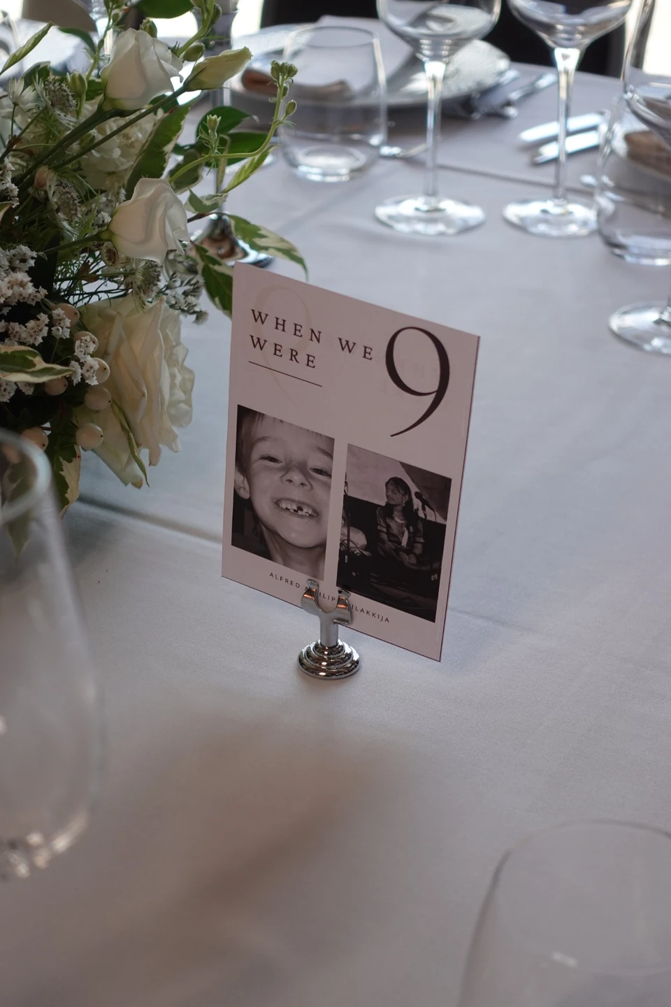 A wedding table number with childhood photographs and flowers